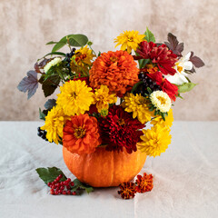 A beautiful autumn bouquet of yellow and red flowers in a pumpkin. The concept of autumn, Thanksgiving Day. Copy space.