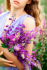 A girl holds a bouquet of lupines.