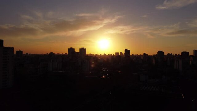 Aerial flight over Buenos Aires City showing dark silhouette of buildings during sunset