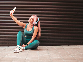 Fitness smiling woman in green sports clothing with pink hair.Young beautiful model with perfect...
