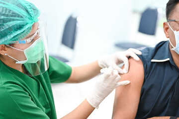 close up doctor's hand injecting for vaccination in the shoulder man patient.Vaccine for protection covid-19(Corona virus) infection.Vaccination for coronavirus treatment.Prevention infectious.