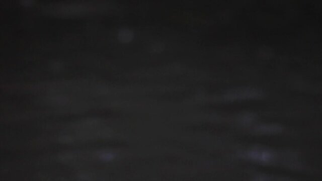 Raindrops drop and splash into a body of water. Dusk. Close up.