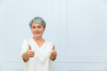 Senior beautiful asian woman wearing casual dress standing and raising fists