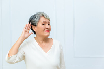 Naklejka premium Senior asian woman with hand over ear listening an hearing to rumor or gossip