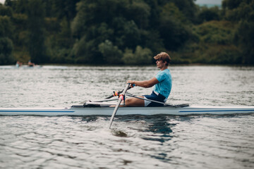 Sportsman oarsman single scull man rower rowing on boat oars side view