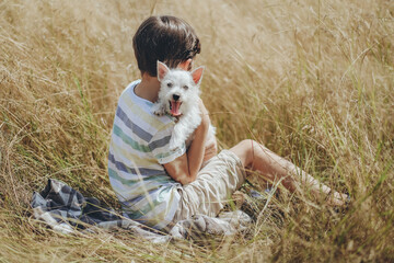 The child has fun with his beloved puppy in the park in summer. Happy childhood.