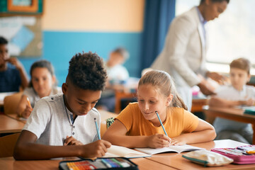 Fototapeta premium Smiling schoolgirl and her African American classmate study during class at elementary school.