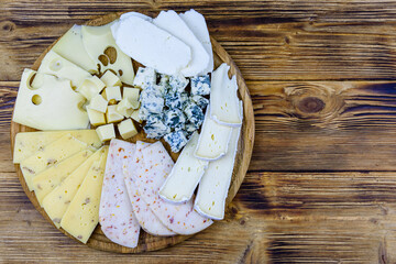 Slices of various types of cheese on a wooden background. Cheese platter