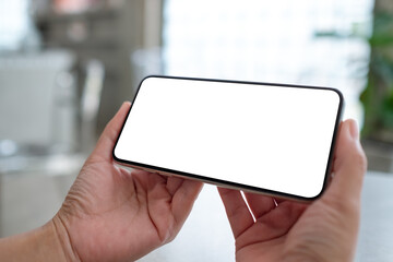 Mockup image of a woman holding mobile phone with blank white desktop screen