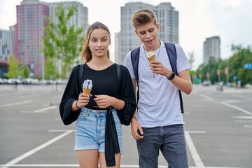 Happy talking couple of teenagers walking together in the city