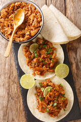 Sinaloan Pork in Chile Sauce Chilorio with tortilla and lime closeup in the slate board on the table. Vertical top view above