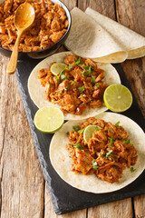 Chilorio is a scrumptious northern Mexican dish made with shredded pork simmered in a delicious chili sauce with spices closeup in the slate board on the table. Vertical