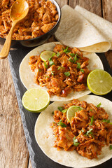 Chilorio is a pork dish from the Mexican state of Sinaloa served with tortilla and lime closeup in the slate board on the table. Vertical