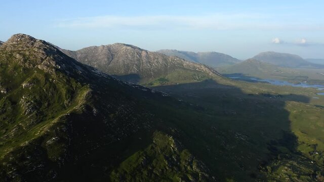 Twelve Bens Mountains, Recess, Connemara, County Galway, Ireland, July 2021. Drone slowly tracks west over Ballynahinch Lake, while ascending and facing north-east into the Garraun mountain complex.