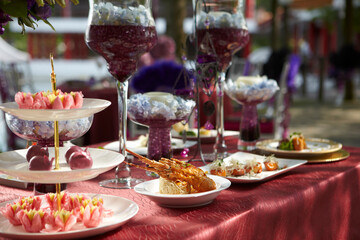 luxury wedding rom banquet sit down buffet party catering in pink purple rose color flower and black feather decoration with fusion halal menu at outdoor beautiful garden