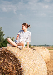 Naklejka na ściany i meble Teenager girl having fun in a wheat field on a summer day.