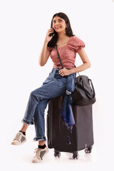 A young travelling woman sitting  her baggage talking on mobile phone. 