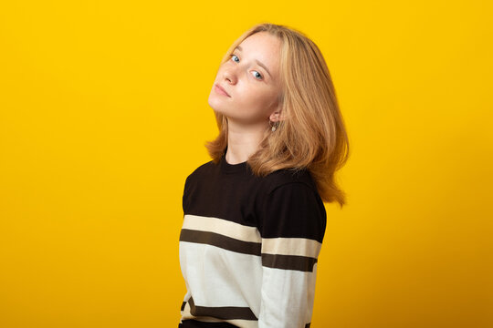 Cute blond teen girl. Studio image of smiling young girl on yellow background.