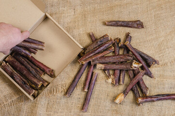 Hand stacks dog treats in a cardboard box. Sticks of dried beef