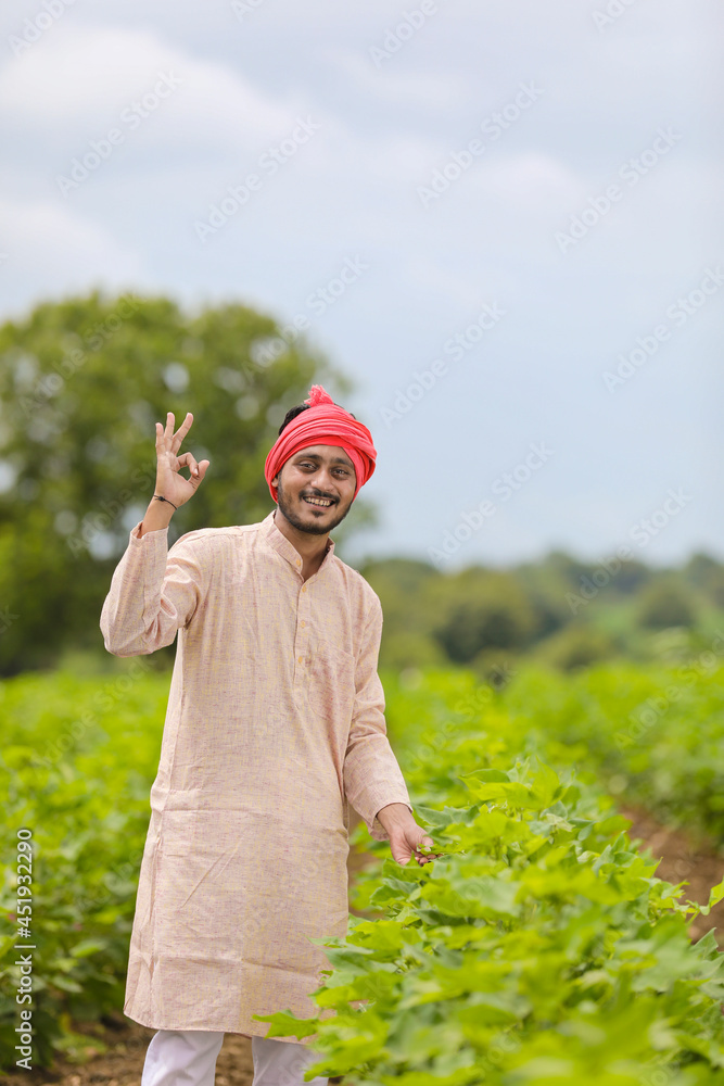 Wall mural Young indian farmer standing at agriculture field.