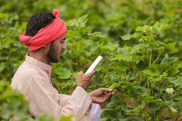 Indian farmer using smartphone at agriculture field.