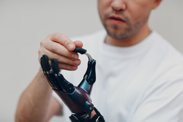 Young disabled man with artificial prosthetic hand put on finger nozzle pad