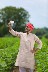 Indian farmer using smartphone at agriculture field.