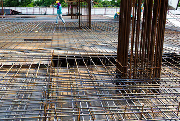 builder worker knitting metal rods bars into framework reinforcement