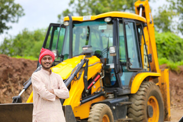 Indian farmer standing with his new earth mover machinery.