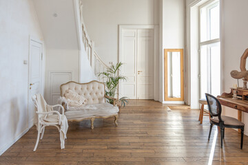 modern interior of a bright room in a two-storey apartment with decorative items in bali style with a balcony. white walls, wood floors and vintage furniture