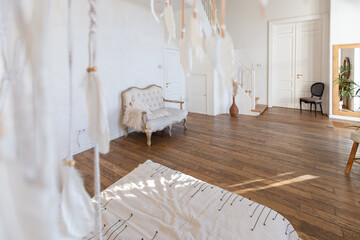 modern interior of a bright room in a two-storey apartment with decorative items in bali style with a balcony. white walls, wood floors and vintage furniture