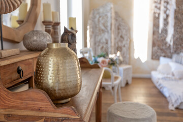 modern interior of a bright room in a two-storey apartment with decorative items in bali style with a balcony. white walls, wood floors and vintage furniture