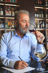 A senior sommelier is tasting red wine.
