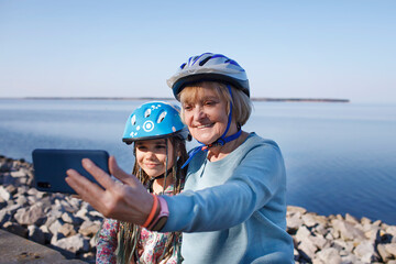 Happy senior woman taking selfie together with grandchild after riding on roller skates, hugs and...