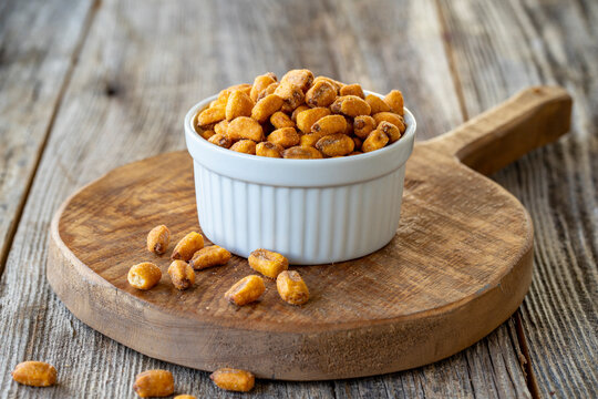 Roasted corn snack. Corn nuts with sauce on wood background. Bulk corn nut grains. Roasted corn nuts on a ceramic plate