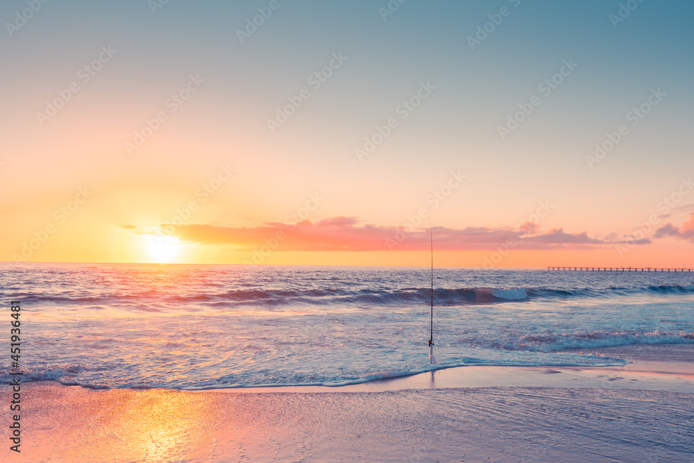 Wall mural surf fishing rod on the sandy beach at sunset, south australia