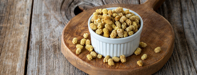 Dried mulberry. Dried mulberry nuts on wood background. Bulk dried mulberry grains. Copy space