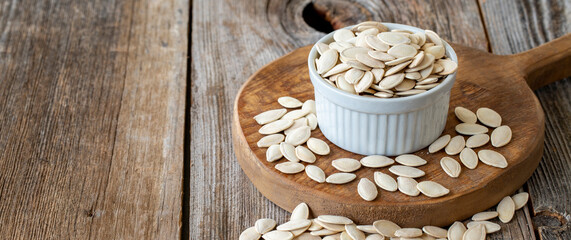 Shelled Pumpkin seeds. Pumpkin seeds on wood background. Bulk Pumpkin Seeds. Pumpkin seeds on ceramic plate. Copy space