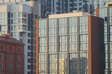 Photo of a part of the facades of modern buildings. Urban landscape at sunset. A pile of glass, concrete and brick.