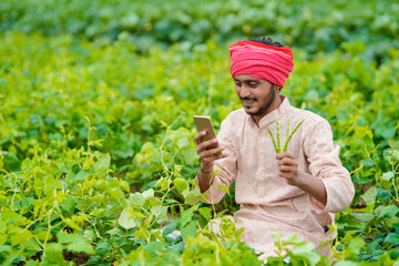 Indian farmer using smartphone at agriculture field.