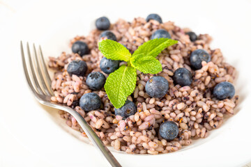 Delicious risotto with blueberries served on white wooden table