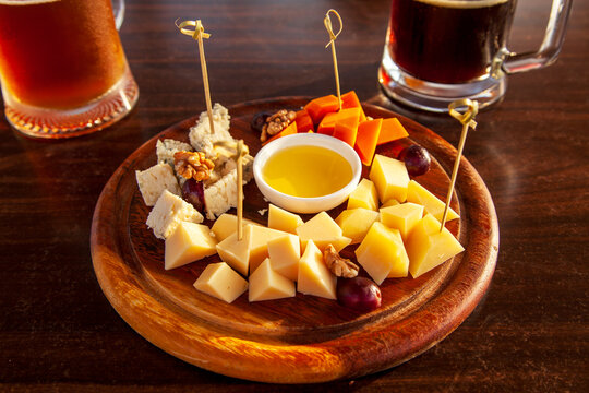 two large mugs of beer and a cheese plate, assorted cheeses