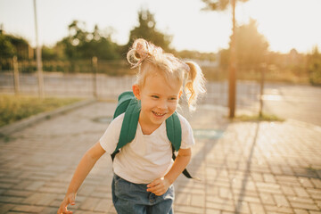 Cute little schoolgirl with school bag on a street