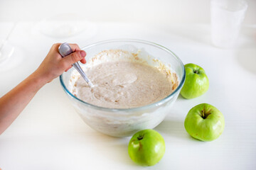 good morning, stir the apple pie dough in a bowl on a white table lit by the sun, horizontal,.
