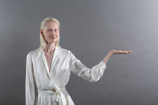 Empty female hand of white caucasian albino blond woman holding and pointing on gray background