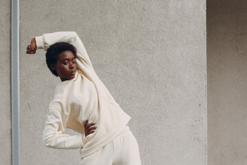 Young african american woman stretching and warming up outdoor street wall. Fitness and outside sport healthy lifestyle concept.