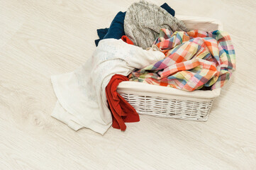 Dirty bedding in a white wicker basket on the floor