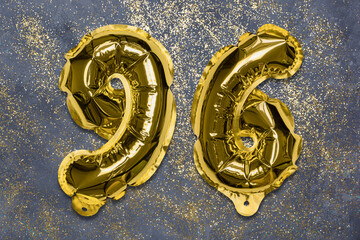 The number of the balloon made of golden foil, the number ninety-six on a gray background with sequins. Birthday greeting card with inscription 96. Numerical digit, Celebration event, template.