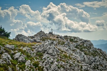Wandern auf der Rax in Niederösterreich - sommerliche Landschaft mit Berg, Fels, Gipfel, Gipfelkreuz und blauem dramatisch bewölktem Himmel