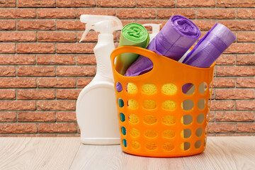 Bottle of dishwashing liquid, basket with garbage bags and sponges.